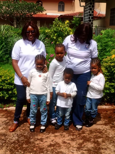 Membres de la fondation, en polo à son logo, avec des enfants dans le jardin du monastère